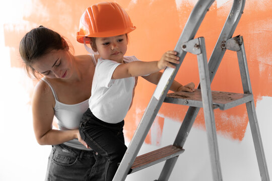 Mom Helps Little Daughter To Climb The Stairs. Home Renovation Concept.