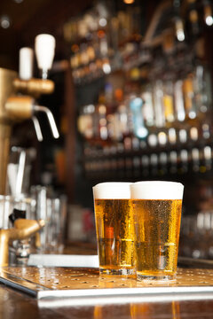 Two draft beers or lagers standing on the bar, freshly drafted and ready to drink
