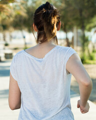 Adult woman in black T-shirt is jogging her back on nature.