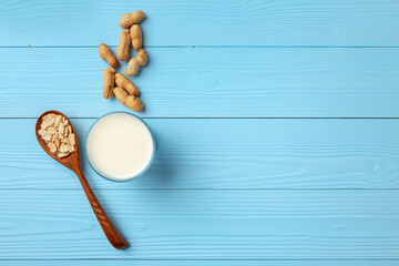 Glass of peanit milk and peanuts in shell on blue wooden background