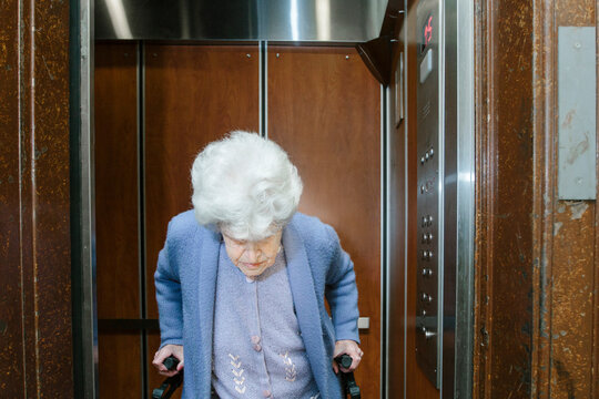 Elderly woman using a walker in elevator of her apartment building