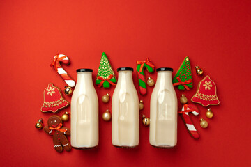 Glass milk bottle and Christmas gingerbread cookies on red background