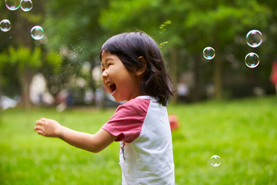 happy little girl playing with soap bubble in the park