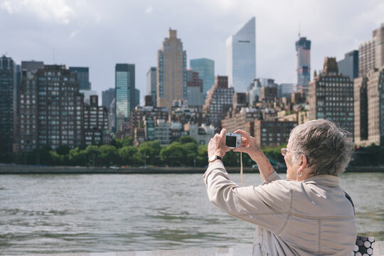 Woman Senior Citizen with old Instamatic Digital Camera Technology Taking Photos of New York City Skyline