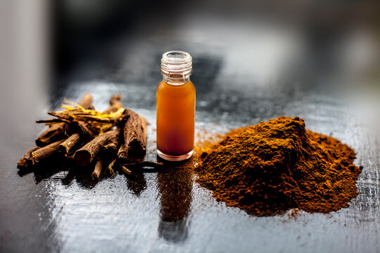 Shot of Rheum emodi or Revand Chini along with its extracted root essence and raw powder on a black glossy surface.