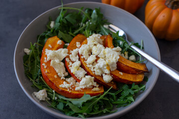 healthy arugula salad with roasted pumpkin and feta cheese