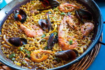 Traditional Valencian paella marinera with shrimps and mussels served on iron frypan