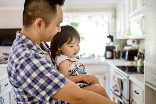 Little Asian girl with her dad in the kitchen