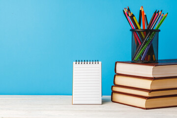 Cup of color pencils and stack of books