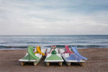 Multicoloured pedal boats with slide on a lonely beach