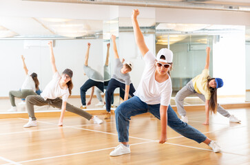 Obraz premium Positive teenage girls and boys training hip hop in dance studio, dance classes for teens
