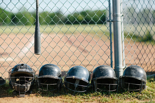 baseball helmets in a row along a fence