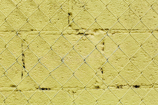 Metal chain link fenc and yellow wall