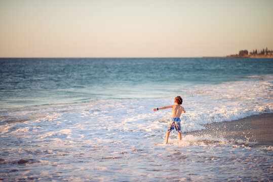 Child riding a skim board at the beach at sunset