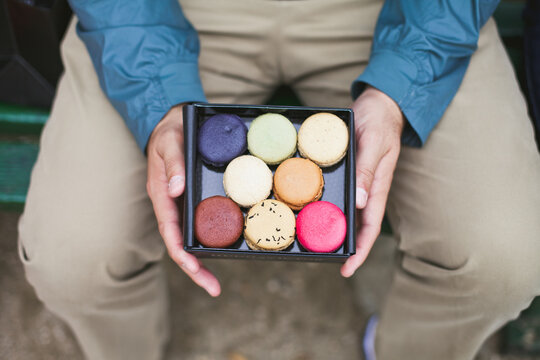 Man holding box of colorful French macaroons