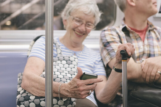 Happy Tech-Savvy Senior Woman Showing Pictures of Her Cat to Other Train Passengers in New York Subway