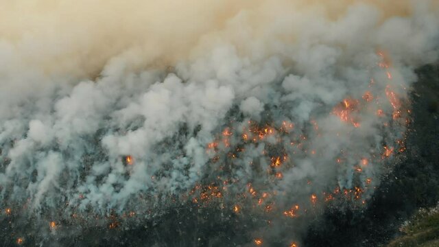 Top aerial view at fire at garbage dump, burning pollutes the environment. Ecological catastrophe and destruction of nature, large fire area
