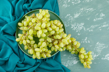 Green grapes in a tray flat lay on plaster and textile background