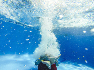 Man jumping into a swimming pool as a cannon ball - underwater view