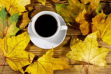 Cup of coffee and autumn maple leaves on wooden table. Top view. Autumn concept