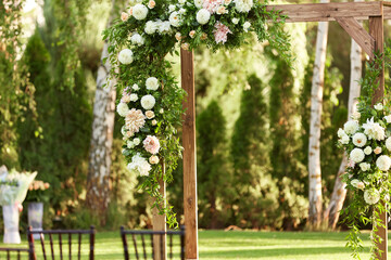 wooden arch for the wedding ceremony decorated with white flowers in sunny summer day