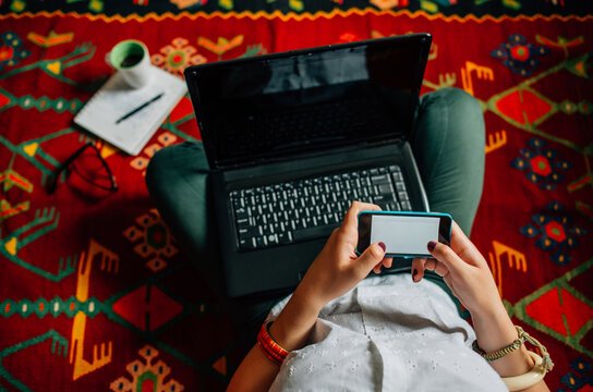 Woman sitting on the colourful rug and texting on her phone
