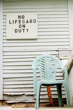 An empty chair sits in front of lifeguard off duty sign
