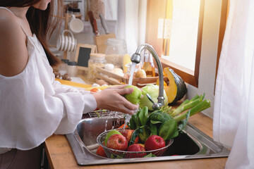 Woman's hands washing green apple to remove pesticides before cooking in kitchen under the tap