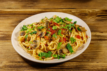 Pasta with mushrooms and tomato sauce on wooden table