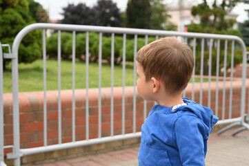 the child looks at the metal fence