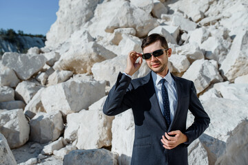 man in classic clothes, jacket, tie and glasses is posing on the mountain.