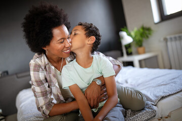 Happy mother playing, having fun, hugging with her son at home