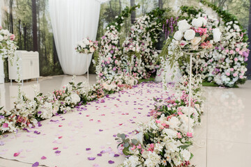 Fototapeta na wymiar Wedding ceremony arch decorated with roses. In the middle is a table with candle composition.