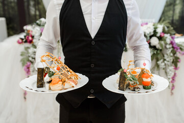 waiter holding plates with appetizer in the restaurant.
