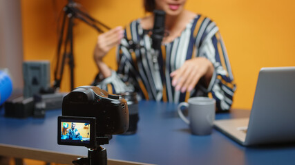 Content creator talking about camera lens in new podcast episode, selective focus on recording camera. new media star influencer on social media talking video photo equipment for online internet web