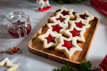 Christmas or New Year homemade sweet biscuits on wooden tray. Traditional Austrian christmas cookies - Linzer biscuits filled with red raspberry jam. Festive decoration. Homemade bakery. Close up