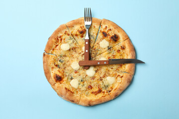 Clock made of pizza and cutlery on blue background