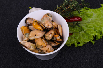 Pickled mussels in the bowl served pepper, garlic and salad