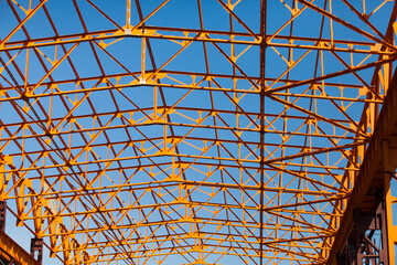 Construction of orange steel building structure. Abstract background of industrial building. Assembling of roof. No people. Close-up.