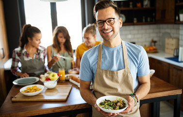 Group of happy friends having fun in kitchen, cooking food together