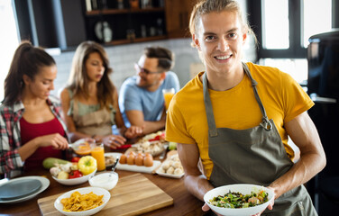 Beautiful happy people, friends is smiling while cooking together in the kitchen