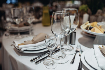   glass, glasses,  table setting, three glasses on the table to the right of the plate, two forks two knives