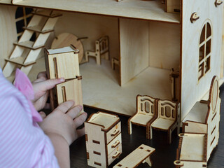 Little girl plays with a wooden doll house