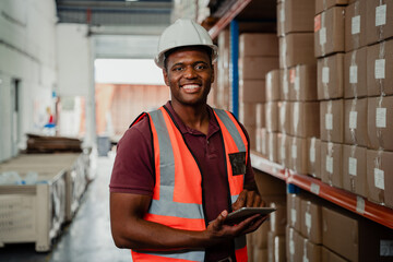 Factory worker smiling holding digital tablet organising parcels in warehouse