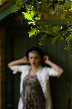 Backlit leaves with the blurry image of a young woman in a hat