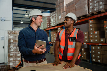 Caucasian and African American males organising shipping information holding tablet in warehouse 