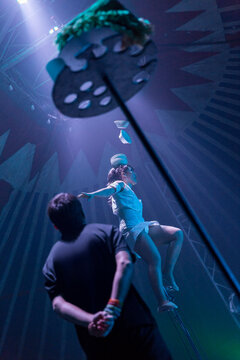 Circus performer on a unicycle balancing multiple bowls on her head