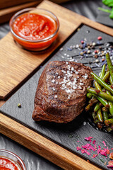 American cuisine. Fried beef steak with garlic fried asparagus. Serving food in a restaurant on a wooden board.