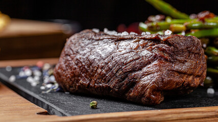 American cuisine. Fried beef steak with garlic fried asparagus. Serving food in a restaurant on a wooden board.