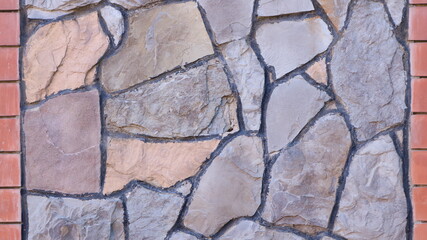 fragment of the surface in the exterior design using treated natural stone and brickwork in the structure